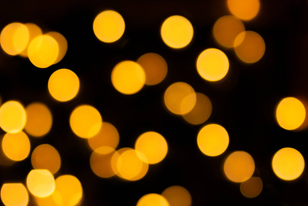 Yellow blurred bokeh on black isolated background. Defocused lights. For overlay design. New Year, Christmas, holiday - Foto, afbeelding