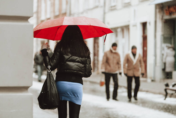 a beautiful girl with an umbrella walks down the street in winter - Foto, afbeelding