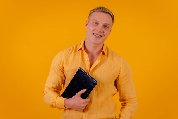 Caucasian blond businessman man on a yellow background, portrait with a tablet smiling, ceo of a company - Foto, immagini