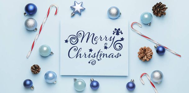 Beautiful Christmas composition with greeting card and decor on light blue background - Photo, Image