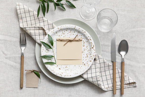 Simple table setting with blank card on light fabric background - Foto, afbeelding