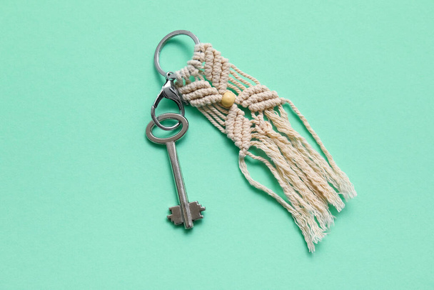 Κλειδί με χειροποίητο βαμβακερό μπρελόκ σε πράσινο φόντο - Φωτογραφία, εικόνα