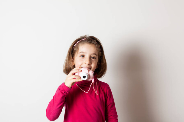Маленька дівчинка фотографує іграшкову фотоапарат на білому тлі
 - Фото, зображення