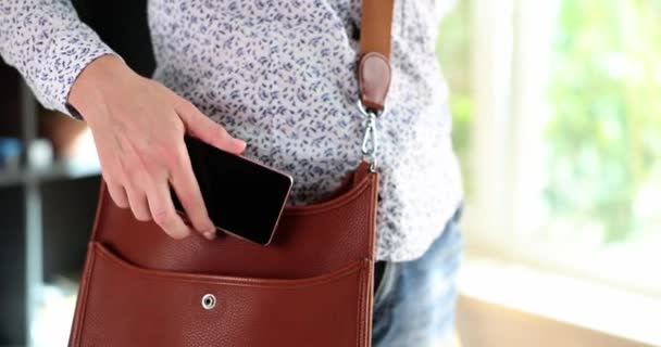 Žena dala telefon do kožené tašky. Módní stylová obchodní taška a smartphone - Záběry, video