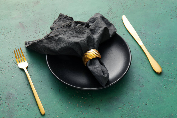 Czarna serwetka w talerzu i sztućce na zielonym tle - Zdjęcie, obraz