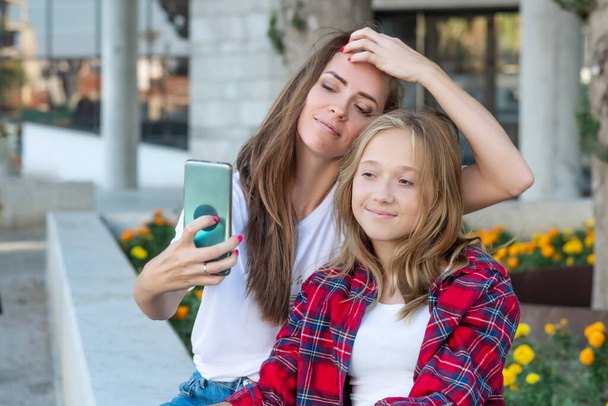 Selfie μαζί. Χαρούμενη χαμογελαστή μητέρα και η έφηβη κόρη της βγάζουν μια φωτογραφία μαζί. - Φωτογραφία, εικόνα