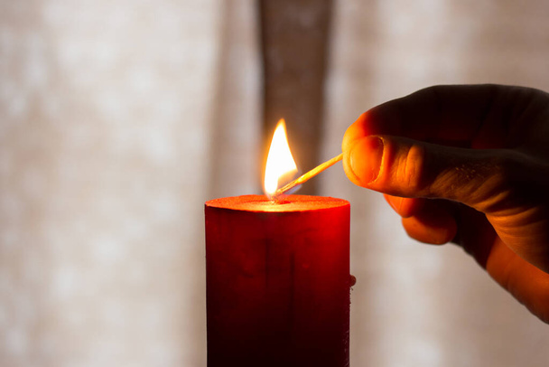 A man lights a candle with a match. Blackout due to war in Ukraine - Fotoğraf, Görsel