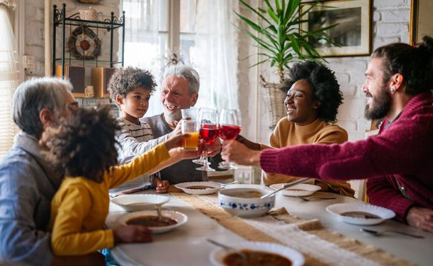 Happy multiethnic multigeneration family having fun together around kitchen table. People holiday food love happiness concept - Foto, afbeelding