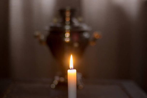 Una candela accesa vicino a un vecchio samovar. Blackout in Ucraina a causa della guerra - Foto, immagini