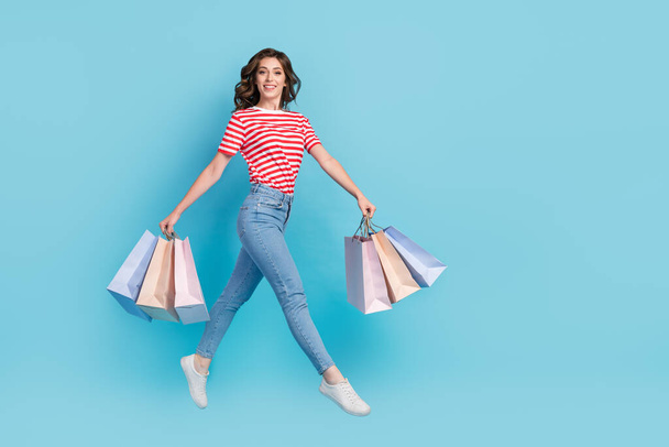 Full length photo of graceful lady client customer go walk empty space carry deliver stylish clothes isolated on blue color background. - Zdjęcie, obraz