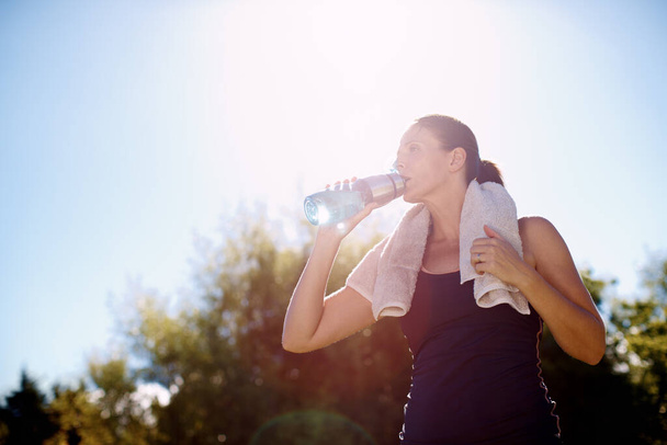 彼女はこの暑い日に水分補給を続ける。ワークアウトの後に水のボトルから飲む魅力的な女性 - 写真・画像