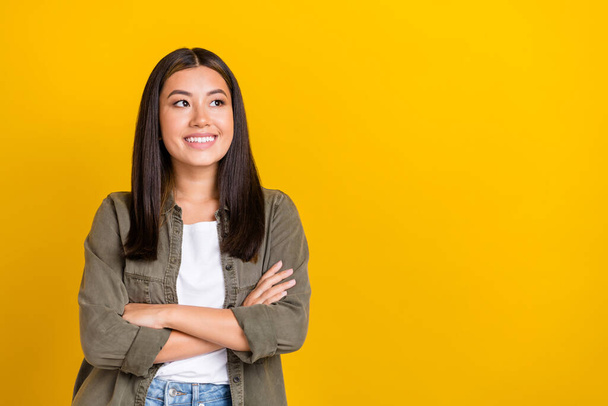 Portrait of adorable gorgeous girl with long hairdo wear khaki shirt arms crossed look empty space isolated on yellow color background. - Foto, afbeelding