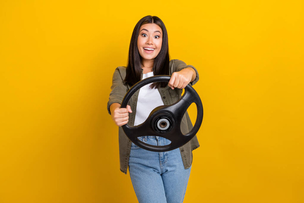 Photo of young overjoyed driver fast speed wear khaki shirt brunette hair chinese woman hold steering wheel drunk isolated on yellow color background. - Photo, Image