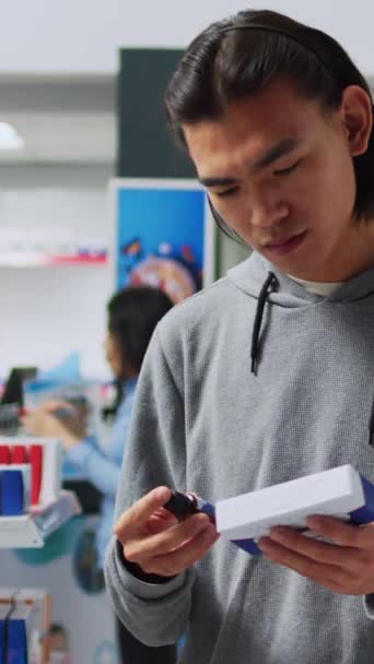 Verticale video: Jonge klant checkt flessen en dozen drugs in de apotheek, kijkt naar de gezondheidszorg geneeskunde op rekken. Onderzoek van farmaceutische producten en vitaminen in verpakkingen, farmaceutische producten - Video