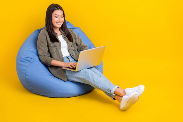 Full length size photo of young student japanese girl sitting beanbag use netbook do remote homework isolated on bright yellow color background. - Fotoğraf, Görsel
