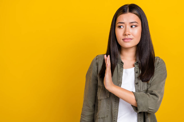 Portrait of sad upset serious woman with long hairdo wear khaki shirt look empty space hold palm isolated on yellow color background. - Фото, зображення