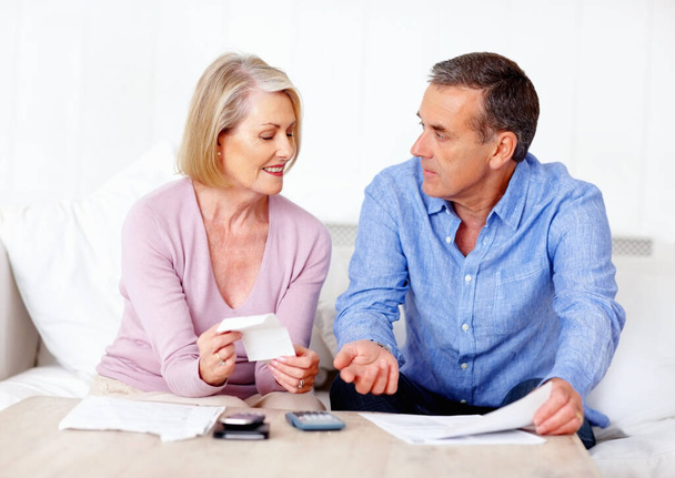 Mature couple calculating expenses using calculator at home. Portrait of a mature couple calculating expenses using calculator at home - Photo, Image