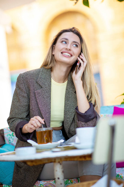 Jovem mulher sorridente conversando com telefone no café - Foto, Imagem