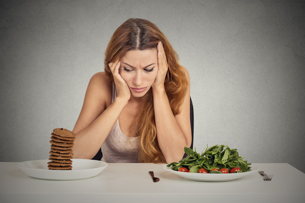 woman tired of diet restrictions deciding to eat healthy food or sweet cookies  - Фото, зображення