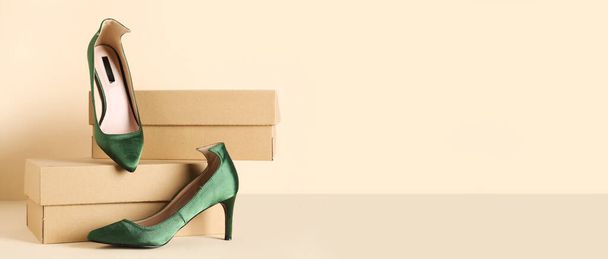 Cardboard boxes and green high-heeled shoes on beige background with space for text - Photo, Image
