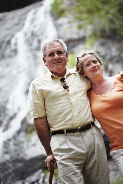 Taking in some fresh air together - Holidays amp Vacations. Portrait of a senior couple standing before a picturesque waterfall - Fotografie, Obrázek