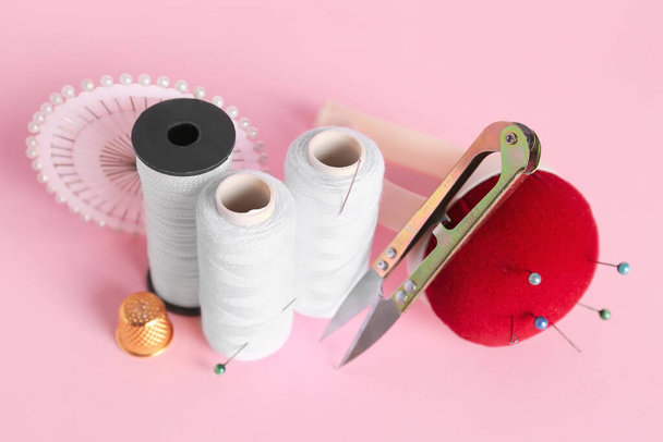 Juego de suministros de costura con carretes de hilo sobre fondo rosa - Foto, imagen