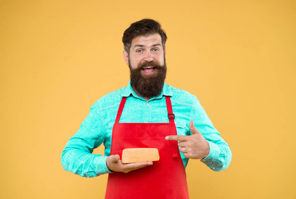 reasonable price and good quality. cheesemaking techniques. cheese maker. hipster with beard in chef apron. Dairy food shop. Online shopping. Gourmet product. happy bearded man hold cheese. - Photo, image
