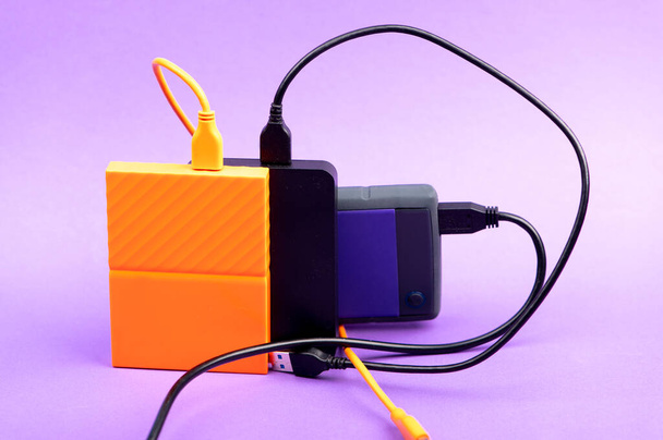 Többszínű külső hordozható merevlemez-meghajtók lila háttérrel - Fotó, kép