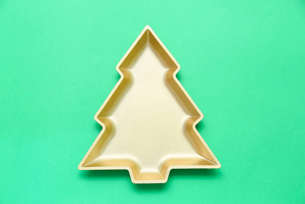 Beautiful plate in shape of Christmas tree on green background - 写真・画像