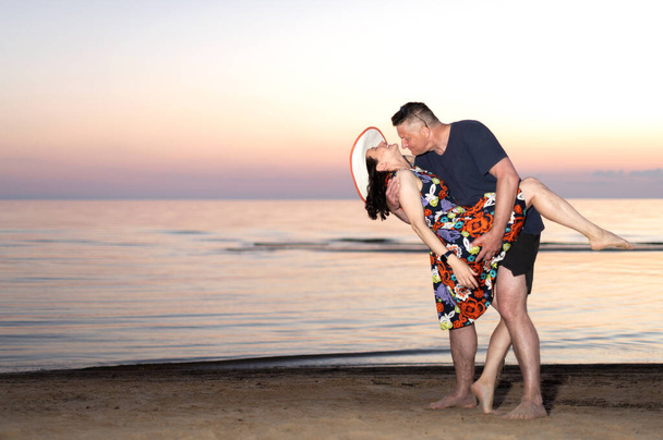 Casal feliz mulher jovem e homem idoso dançando no pôr do sol fundo do mar - Foto, Imagem