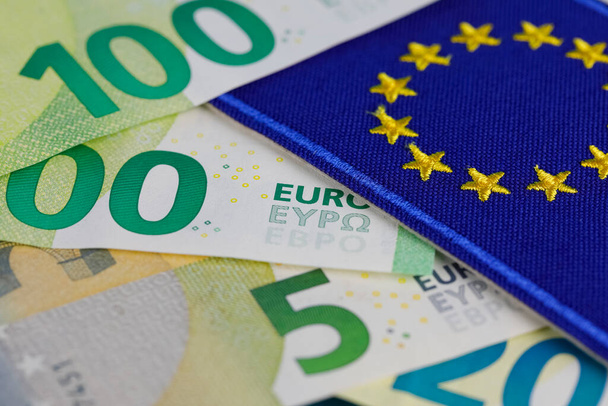 Τα τραπεζογραμμάτια ευρώ με τη σημαία της Ευρωπαϊκής Ένωσης τοποθετούνται το ένα δίπλα στο άλλο. Τα τραπεζογραμμάτια ευρώ δεν είναι κατασκευασμένα από χαρτί, αλλά από ίνες καθαρού βαμβακιού για τη βελτίωση της ανθεκτικότητάς τους. Νόμισμα σε ευρώ. - Φωτογραφία, εικόνα