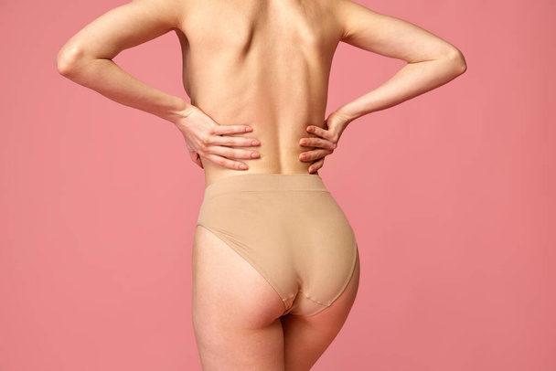 Cropped back view image of female body, back buttocks in beige underwear isolated over pink studio background. Concept of beauty, fitness, spa, cosmetology, skin and body care, health, plastic surgery - Foto, imagen