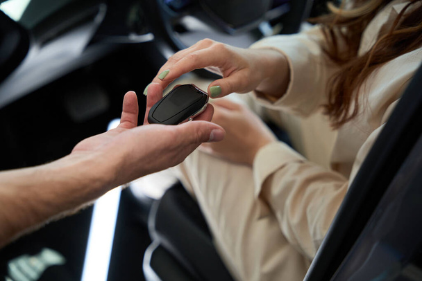 Zugeschnittenes Foto einer weiblichen Hand, die einer Verkäuferin Auto-Fernbedienung abnimmt - Foto, Bild