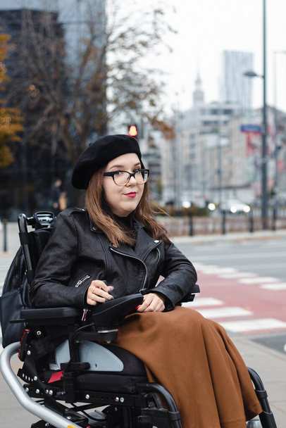 Brunette woman sitting in wheelchair on city street. High quality photo - Fotoğraf, Görsel