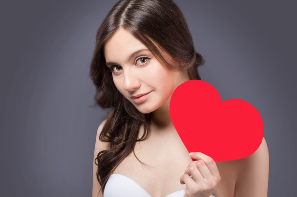 Love and valentines day woman holding heart smiling cute and adorable. Valentine's Day. Beautiful smiling woman with a gift in the form of heart in his hands - Φωτογραφία, εικόνα