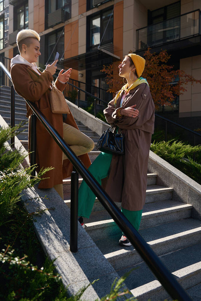 Женщина в осенней одежде позирует для фото другу перед большим зданием - Фото, изображение