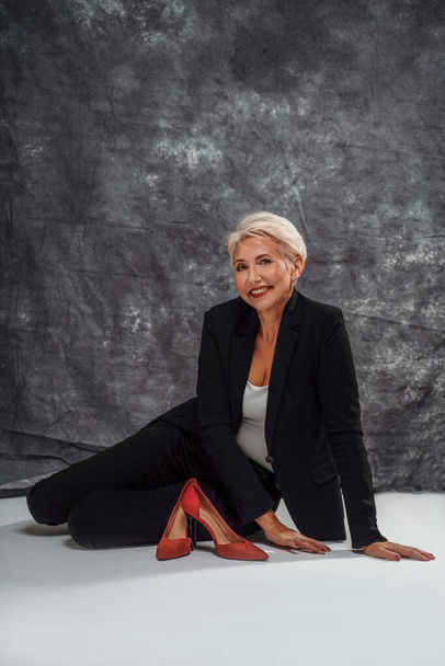Happy stylish woman with short blonde hairstyle and glamour makeup looking and smiling to the camera, relaxing after work. Elegant businesswoman. Studio shot. Copy space. - Φωτογραφία, εικόνα