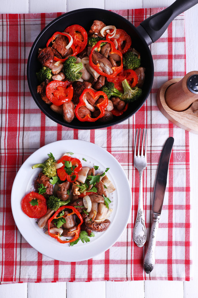Braised wild mushrooms with vegetables and spices in pan and plate on table - Foto, afbeelding