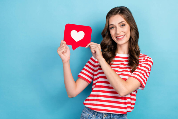 Photo of sweet adorable lady wear striped t-shirt holding heart like card empty space isolated blue color background. - Fotografie, Obrázek
