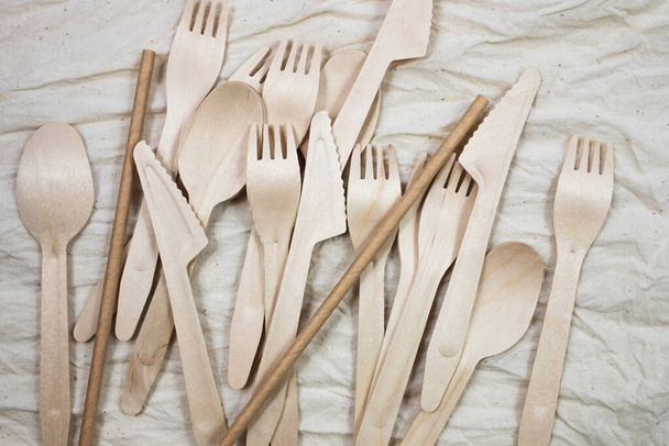 Cucharas de bambú desechables, cuchillos y tenedores sobre un fondo de lona. - Foto, Imagen