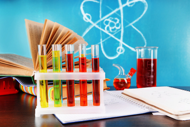 Glassware with chemical agent on desk, on green blackboard background - Foto, imagen