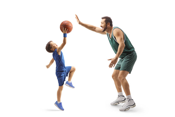 Full length profile shot of an adult basketball player playing basketball with a child isolated on white background - Photo, Image