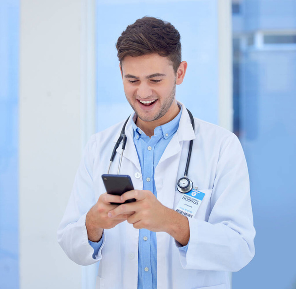 Doktor, férfi és telefon mosollyal SMS-ezéshez, kommunikációhoz, beszélgetéshez és jó kapcsolatokhoz a kórházban. Boldog férfi egészségügyi vagy egészségügyi szakember mosolyog távközlési szolgáltatás a klinikán. - Fotó, kép