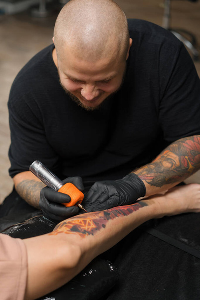 Primer plano: proceso de tatuar a una mujer en su pierna. Hombre tatuaje artista hacer un tatuaje - Foto, imagen