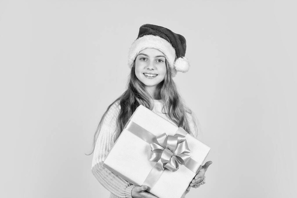 my present. xmas party celebration. happy new year. christmas shopping online. time for discount. smiling kid hold purchase. presents and gifts from santa claus. small girl santa at yellow background. - Фото, зображення