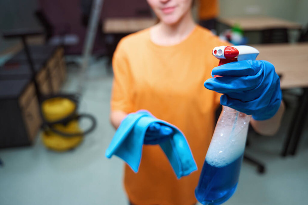 Καλλιεργημένη φωτογραφία καθαρίστριας κυρίας που ποζάρει με μπουκάλι διαλύματος καθαρισμού παραθύρων και πανί για σκούπισμα - Φωτογραφία, εικόνα