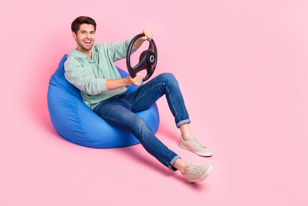Full length photo of cheerful man sit chair wear stylish clothes rejoice new fast car empty space isolated on pink color background. - Zdjęcie, obraz