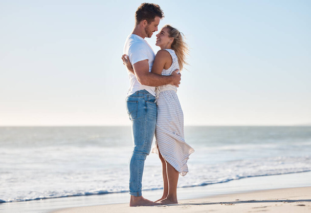 Umarmung, Strand und glückliches Paar bei einem romantischen Liebesurlaub am Meer in Australien. Reisen, Romantik und junge Männer und Frauen, die sich während eines Flitterwochen-Urlaubs oder Abenteuers am Meer umarmen - Foto, Bild