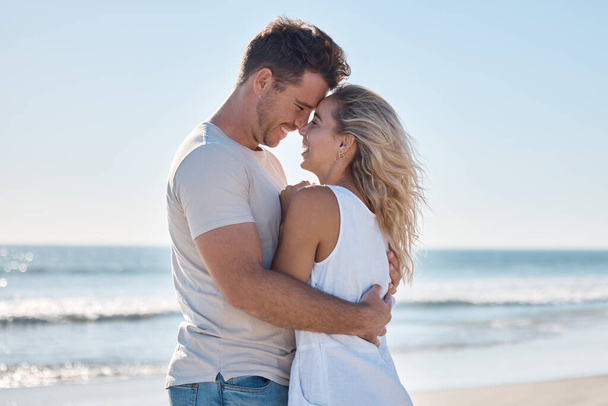Couple, love and hug in relationship at the beach for summer vacation or romantic bonding in the outdoors. Happy man and woman hugging with smile together in loving embrace for romance by the ocean. - Foto, Bild