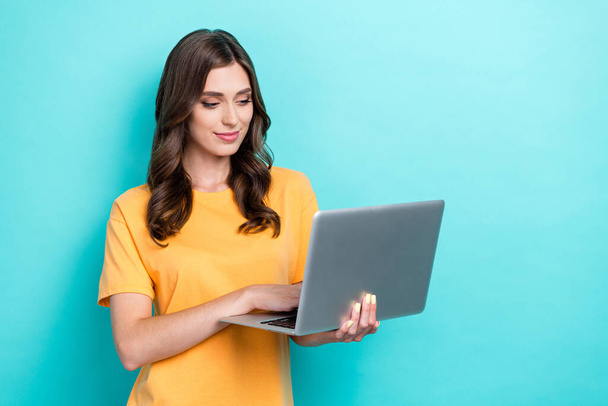 Photo of young attractive gorgeous nice girl businesswoman wear yellow t-shirt hold laptop typing professional worker isolated on cyan color background. - 写真・画像